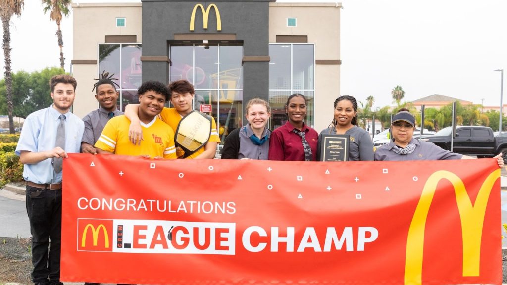 Image showing McDonald's Gaming League competitors holding red and yellow banner outside restaurant