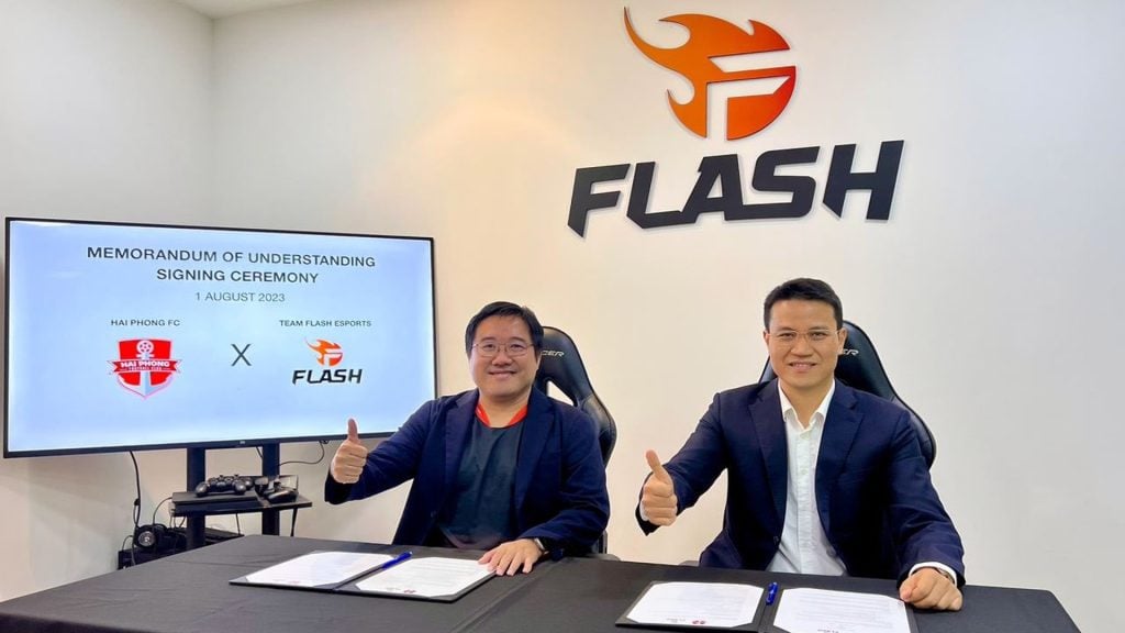 Screenshot of Team Flash and Hai Phong FC representatitves sat at table with Team Flash logo on wall
