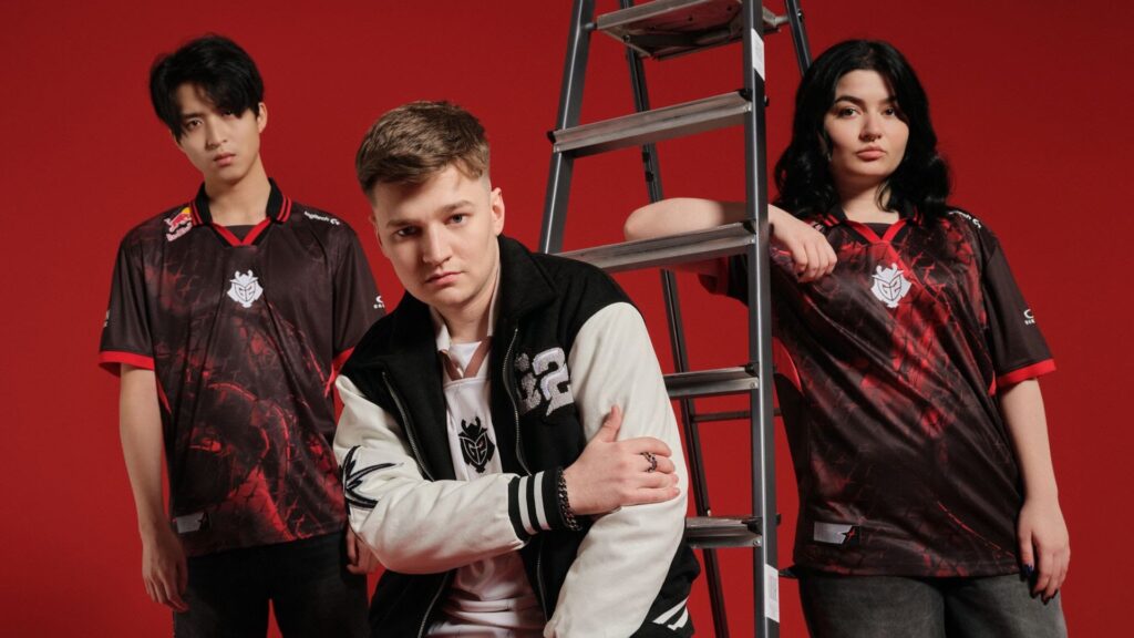 Image of people wearing G2 Esports 2025 merchandise while posing near a ladder.